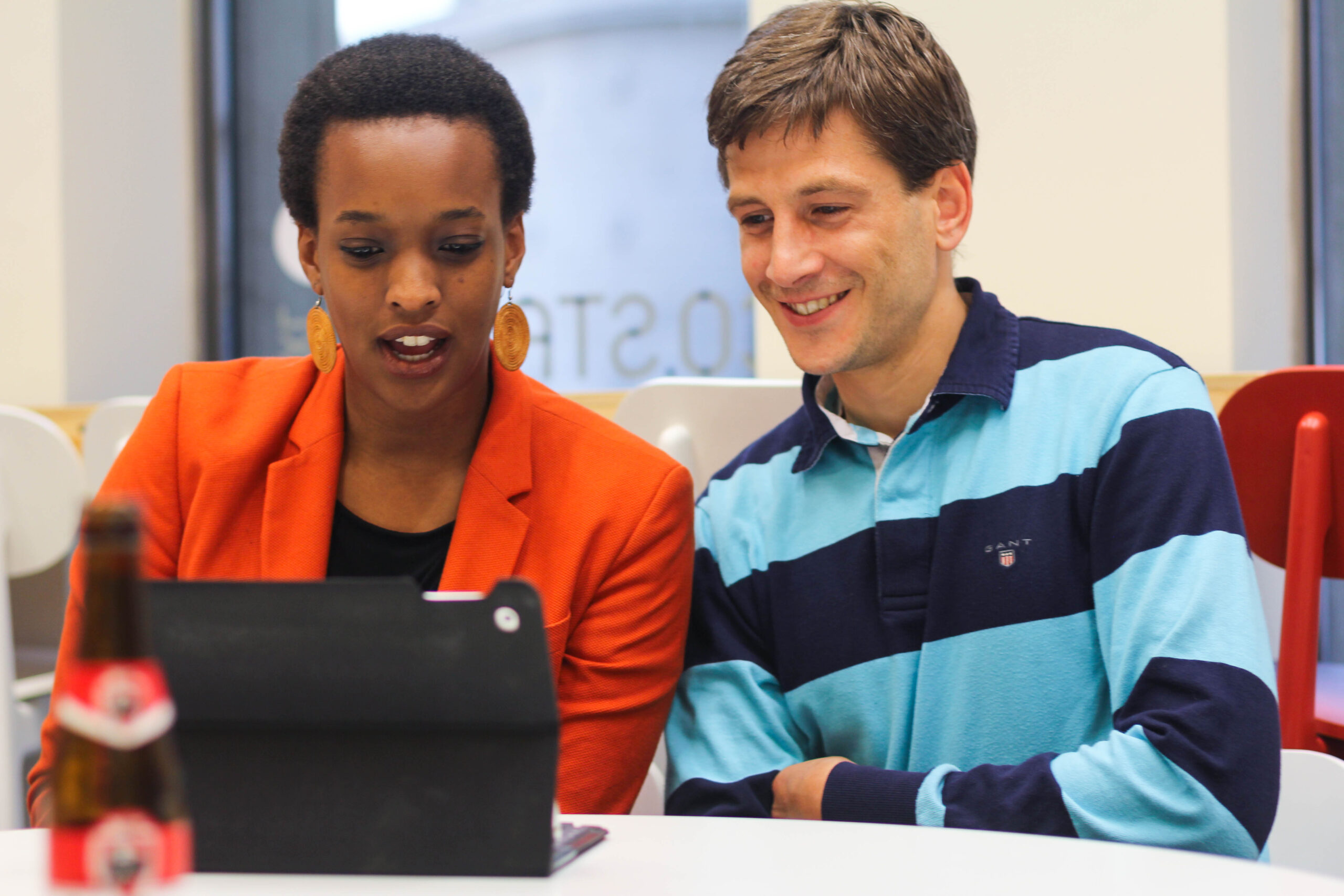 2 personnes échangent en regardant un contenu sur une tablette